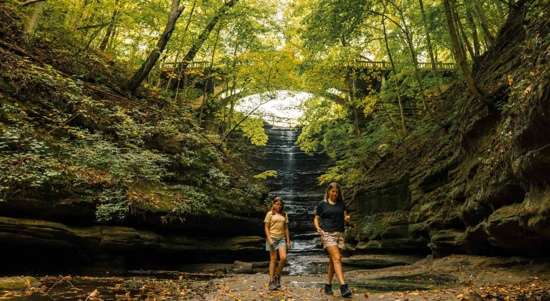 Zwei Mädchen spazieren vor einem Wasserfall im Matthiessen State Park