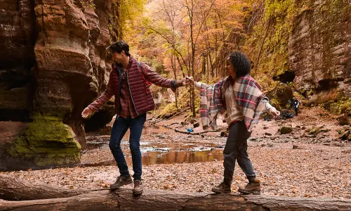 Ein Ehepaar wandert im Herbst durch den Wald.