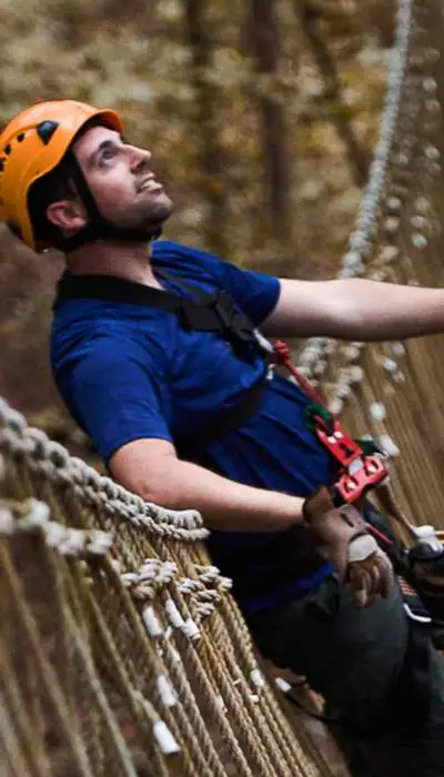 Kletterer an Klettergurten beim Überqueren einer Brücke.