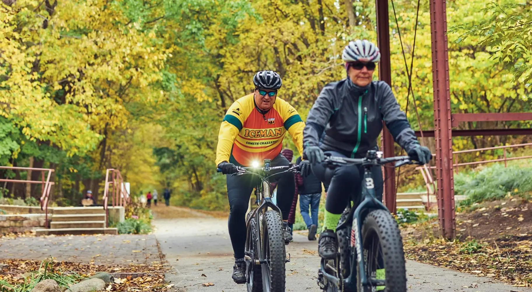 Zwei Radfahrer fahren auf einem Waldweg unter einer alten Holzbrücke
