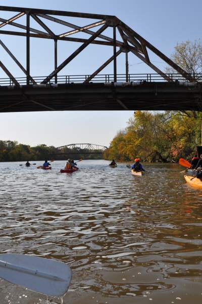 Eine Gruppe von Menschen paddelt in Kanus den Fluss hinunter