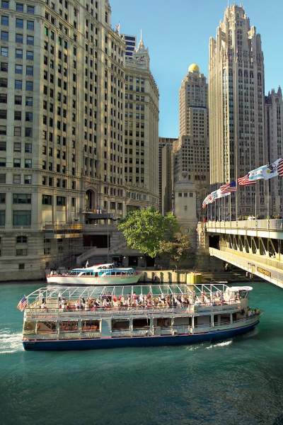 Ein architektonisches Ausflugsboot fährt unter einer Brücke in Chicago hindurch