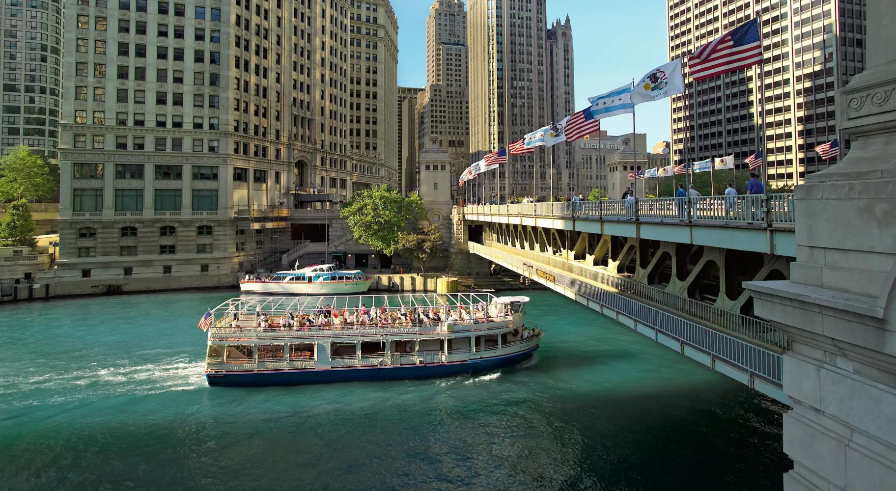 Ein architektonisches Ausflugsboot fährt unter einer Brücke in Chicago hindurch