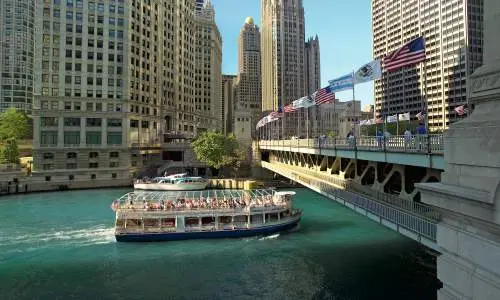 Ein architektonisches Ausflugsboot fährt unter einer Brücke in Chicago hindurch