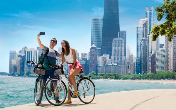 Ein Paar radelt auf dem Weg am See entlang und macht ein Foto