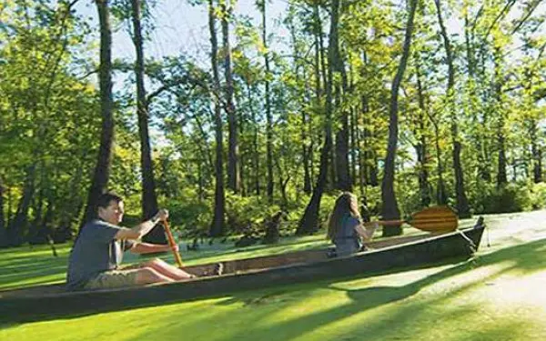 Ein seitliches Bild eines Vaters und einer Tochter, die mit dem Kanu einen Sumpffluss hinunterfahren