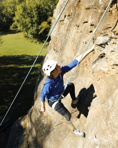 Ein Kletterer reicht die Hände von einem Felsen im Giant City State Park