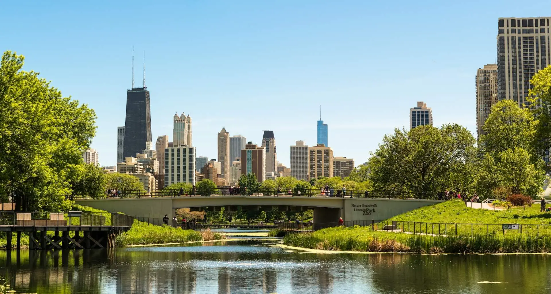 Grünes Land und Bäume mit einer Brücke und städtischen Gebäuden dahinter