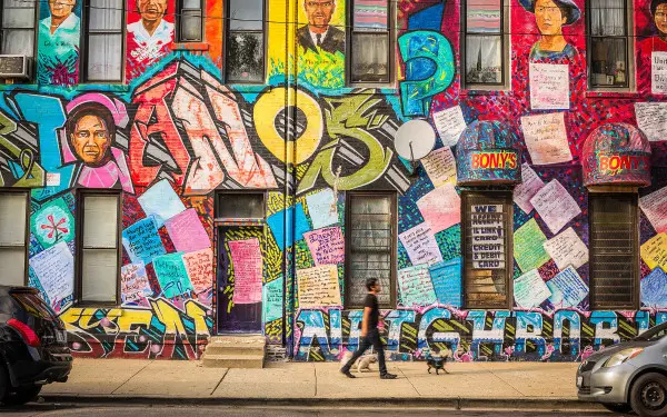 Eine Person mit einem Hund, die vor einer Wandmalerei zum mexikanischen Kulturerbe spazieren geht