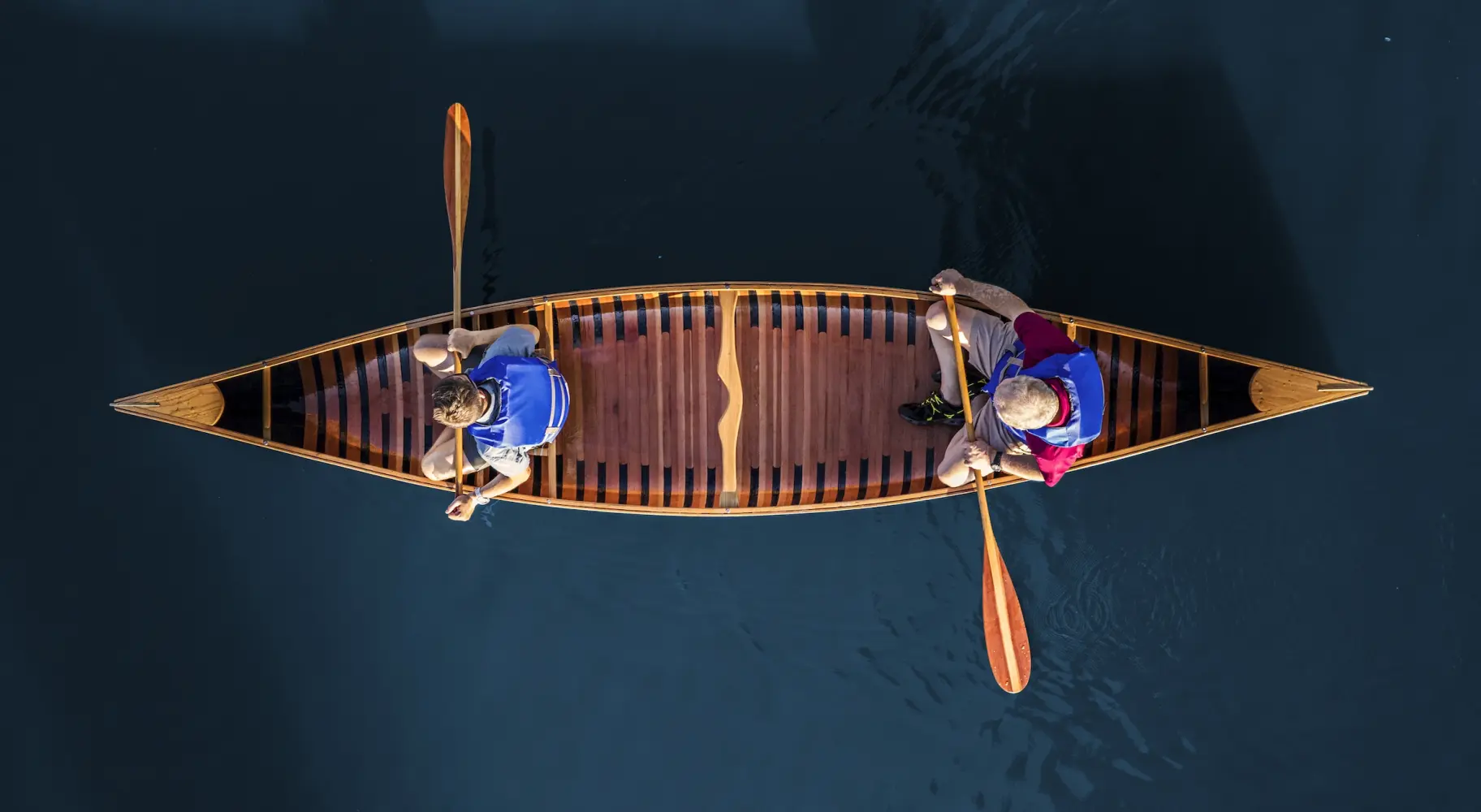 Luftaufnahme von zwei Personen in einem Kanu auf blauem Wasser
