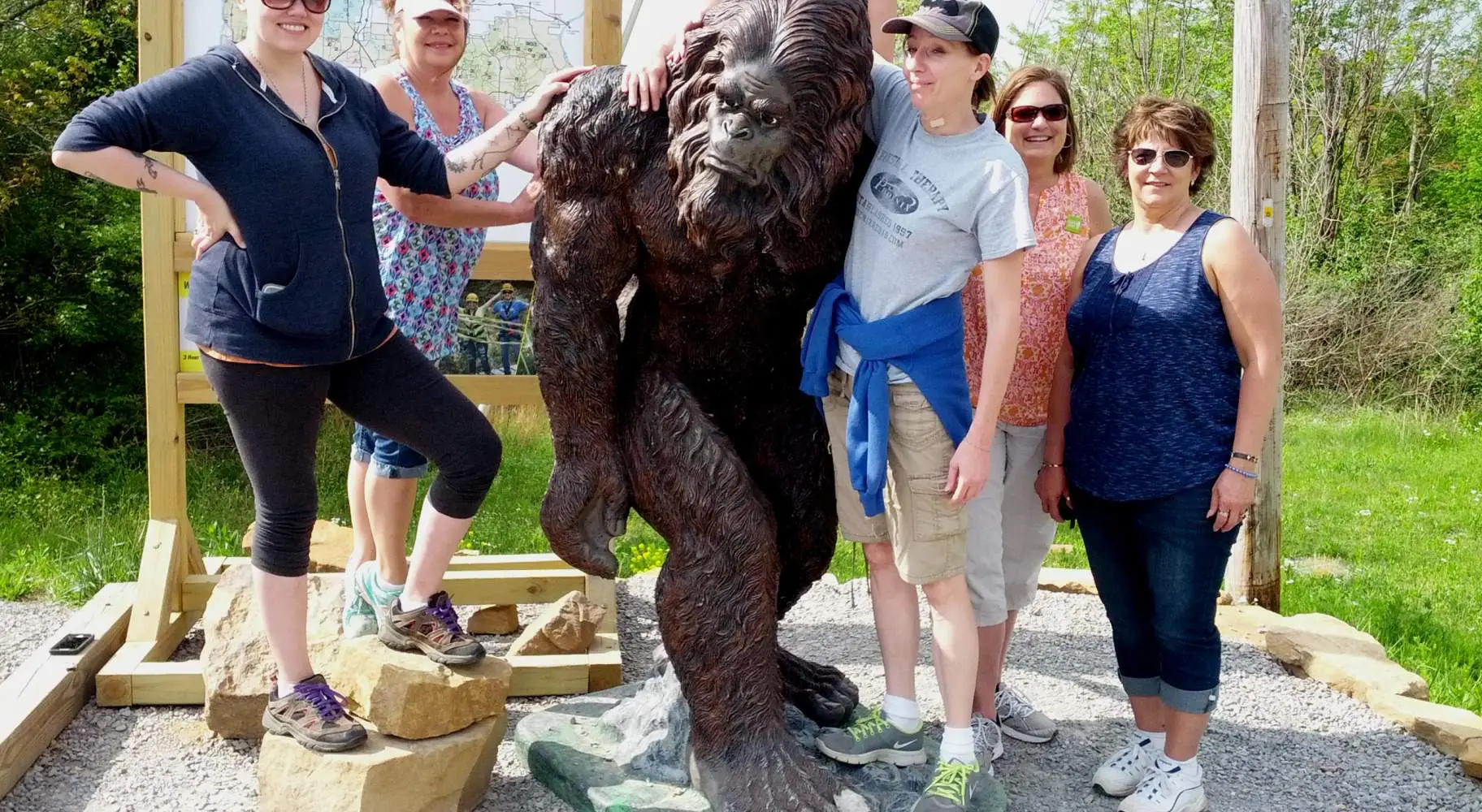 Eine Gruppe von sechs Frauen posiert mit der Statue eines Sasquatch namens Sassy