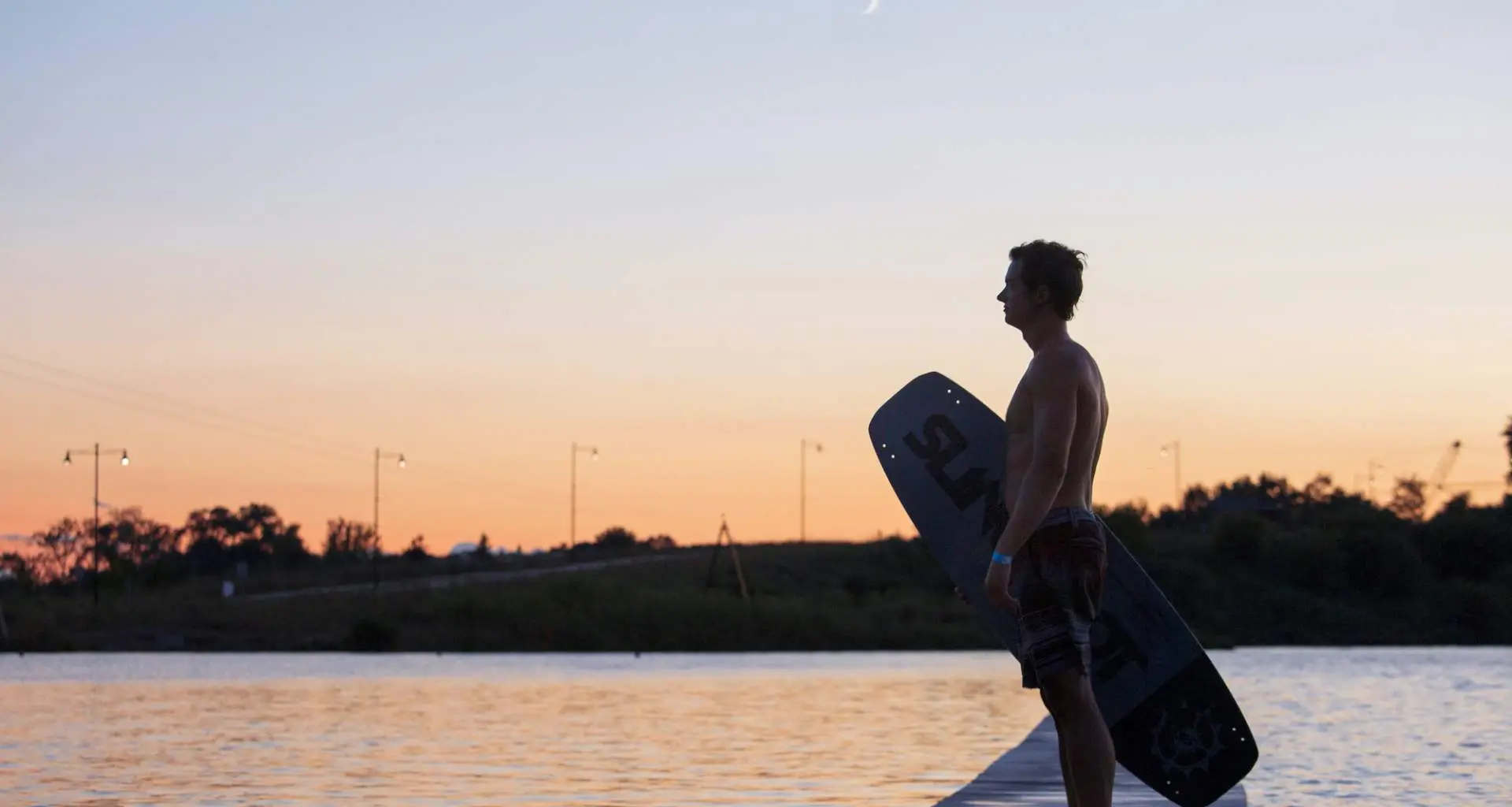 Wakeboarder steht in der Abenddämmerung neben dem Quarry Cable Park