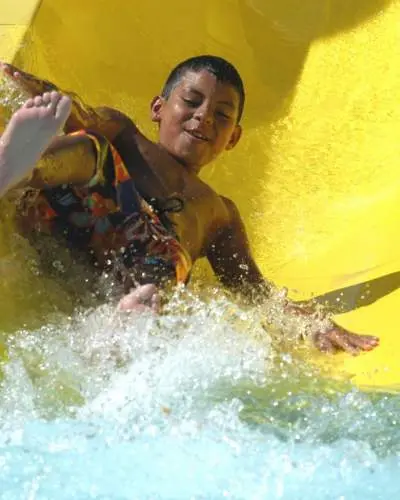 Kind kommt die gelbe Great America Hurricane Harbor Wasserrutsche herunter