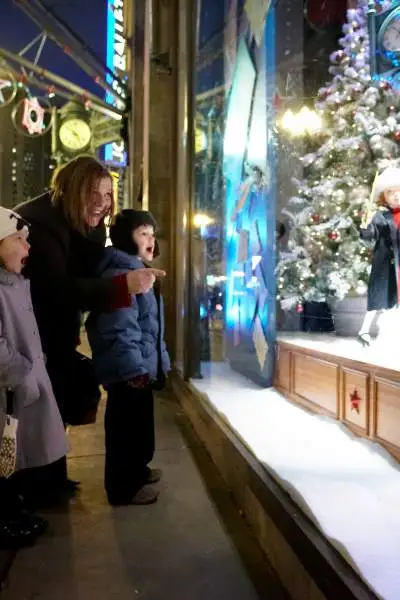 Frau und Kinder schauen nach draußen in ein Schaufenster