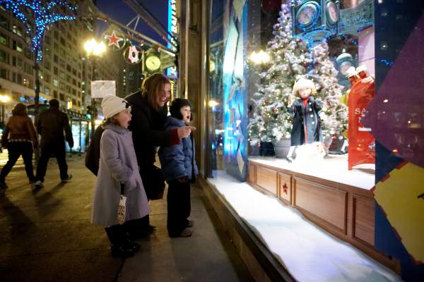 Frau und Kinder schauen nach draußen in ein Schaufenster