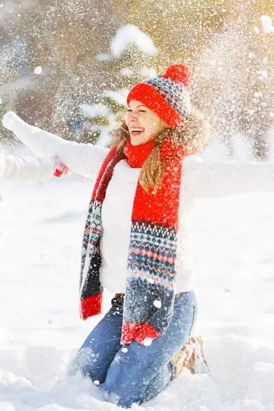 Eine Mutter mit ihrem Kind, die sich dem Wetter entsprechend warm anzieht und Schnee in die Luft wirft