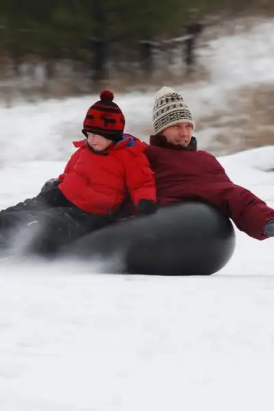 Ein Mann und ein Junge beim Snowtubing auf dem Berg Hoy