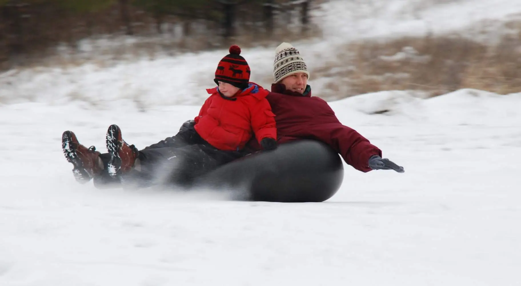 Ein Mann und ein Junge beim Snowtubing auf dem Berg Hoy