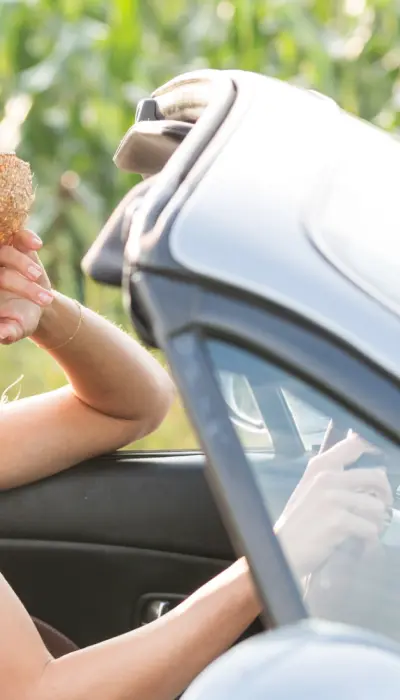 Mädchen in einem Cabrio fahren an Maisfeldern vorbei.