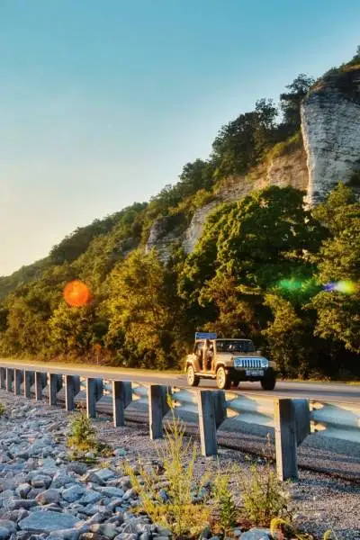 Der Sonnenaufgang über dem Wasser und ein Auto auf der Straße daneben