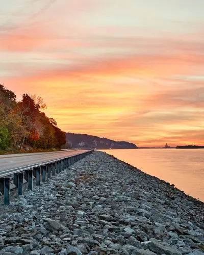 Sonnenuntergang über dem Wasser und einer Straße am Flussufer