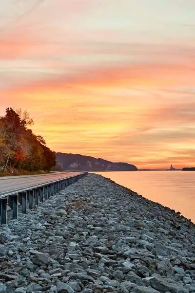 Sonnenuntergang über dem Wasser und einer Straße am Flussufer