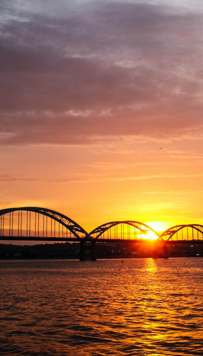 Sonnenuntergang über dem Fluss mit Brücke