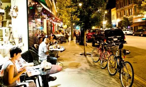 Menschen lesen und essen vor Geschäften entlang der Straße