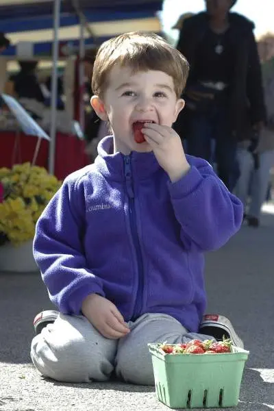 Ein Junge isst Erdbeeren auf einem Markt in Illinois