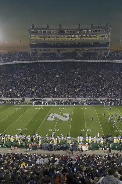 Ein großes College-Football-Stadion am Abend vor einem Spiel, die Tribünen sind voll mit Zuschauern
