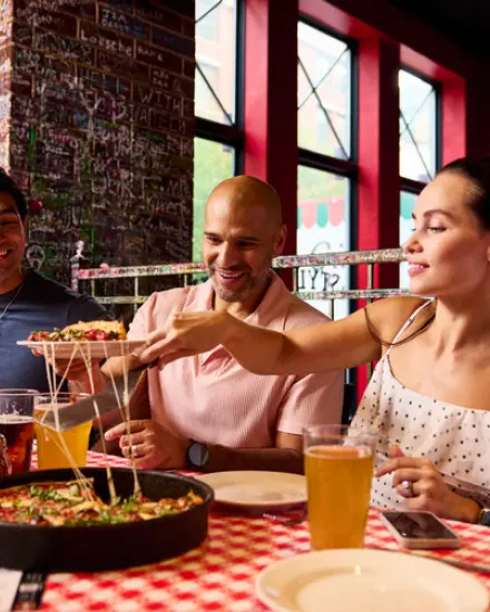 Freunde, die in einem Restaurant gemeinsam Pizza und Getränke genießen.