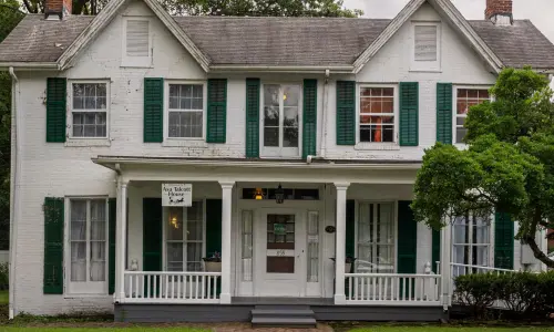 Vorderansicht eines historischen Hauses und einer unterirdischen Eisenbahnstrecke.